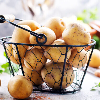 raw potato in metal basket and on a table