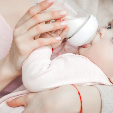 Young,Mother,Feeding,Her,Little,Cute,Baby,Daughter,With,Bottle